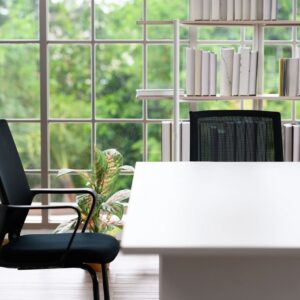 Corner of the desk in the room has a chair and bookshelf. Can see the natural scenery outside the window.