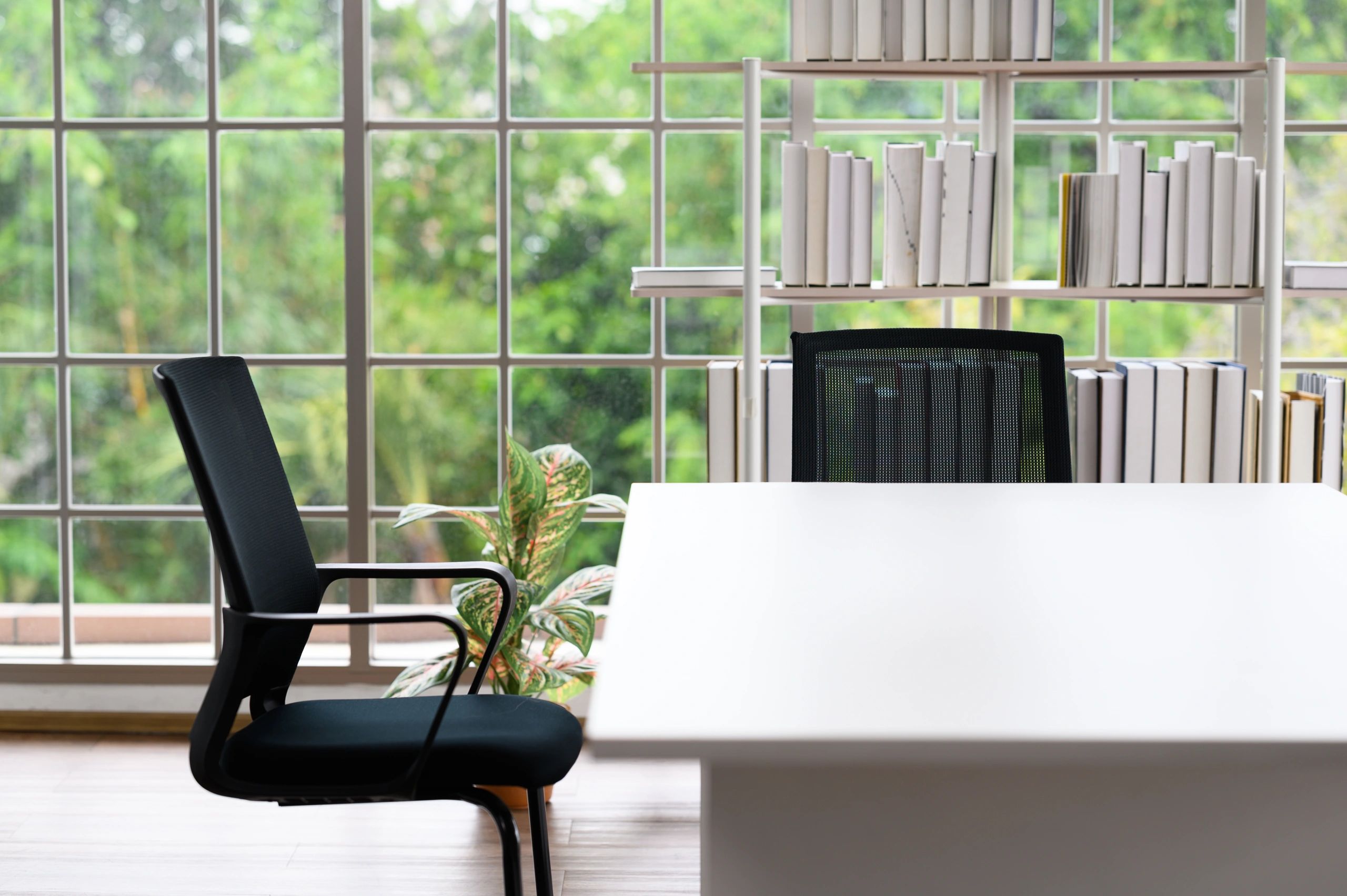 Office desk corner with chair bookshelf and window view